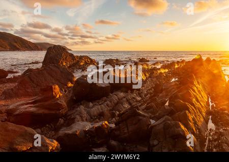 Ein feuriger Sonnenuntergang beendet einen angenehmen Sommertag an der Küste Cornwalls. Widemouth Bay, Cornwall Stockfoto