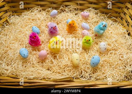 Spielen Sie osterküken und Eier auf einer strohhaltigen Bettwäsche und einer Vielzahl von Farben Stockfoto