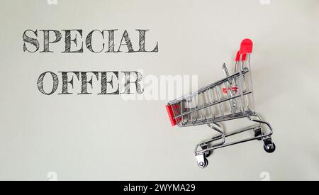 Ein Warenkorb mit rotem Griff befindet sich auf weißem Hintergrund mit der Aufschrift „Sonderangebot“ darunter Stockfoto