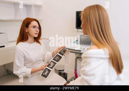 Rückansicht einer nicht erkennbaren jungen Patientin, die von einer qualifizierten Frauenärztin zu Untersuchungsergebnissen und Ovarialsonographie konsultiert wird. Stockfoto