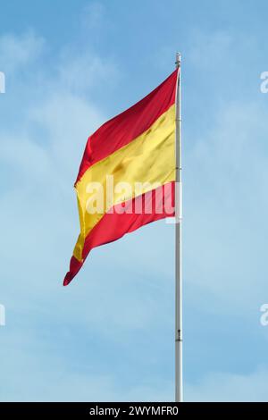 Die Nationalflagge Spaniens fliegt stolz unter einem blauen Himmel, ihre roten und gelben Farben leuchten in der Sonne und erinnern an den Geist und die Tradition des Grafen Stockfoto