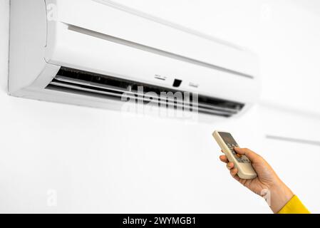 Hand, die Fernbedienung auf die Klimaanlage. Stockfoto