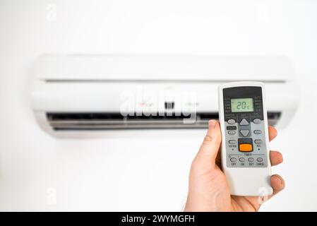 Fernbedienung vor der Klimaanlage mit der Hand halten. Stockfoto