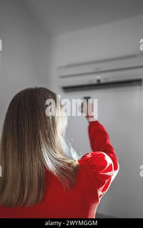 Frau mit Fernbedienung für die Klimaanlage. Stockfoto