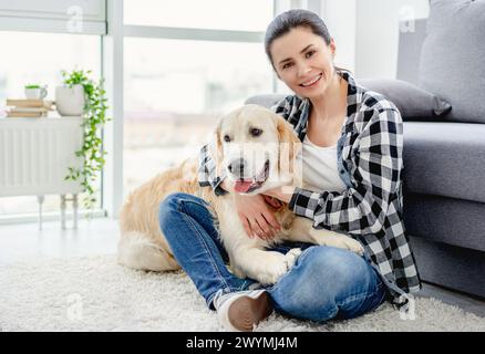 Hübsche Frau kuschelt niedlichen Hund im Lichtraum Stockfoto