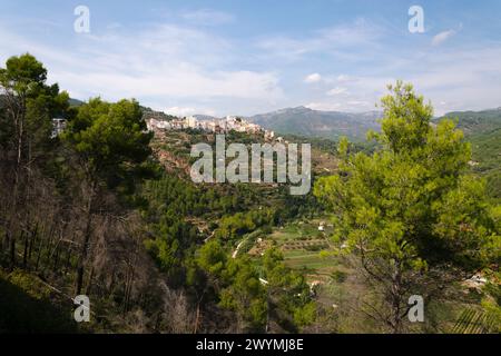 Zwischen den Bäumen ein Blick auf das Dorf Lucena del Cid umgeben von der Natur an einem Tag mit blauem Himmel und Wolken, Castellon, Spanien Stockfoto