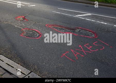 Graffiti auf den Straßen von Chichester, West Sussex, Großbritannien, beschweren sich nach Jahren der Vernachlässigung über die Topflöcher und den Zustand der Straßen. Stockfoto