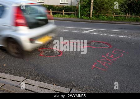 Graffiti auf den Straßen von Chichester, West Sussex, Großbritannien, beschweren sich nach Jahren der Vernachlässigung über die Topflöcher und den Zustand der Straßen. Stockfoto