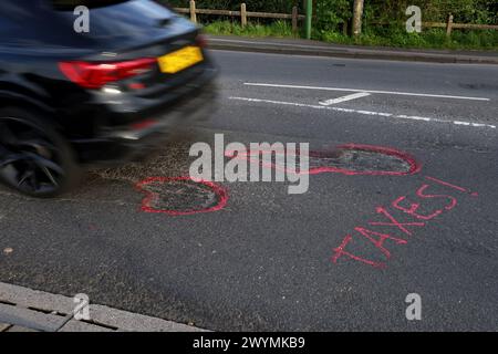 Graffiti auf den Straßen von Chichester, West Sussex, Großbritannien, beschweren sich nach Jahren der Vernachlässigung über die Topflöcher und den Zustand der Straßen. Stockfoto