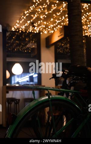 Charaktervolles Fahrrad vor einem Restaurant am Abend. Lichter leuchten im Hintergrund Stockfoto