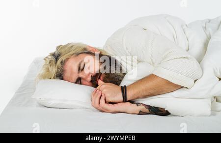 Gesundes Schlafkonzept. Bärtiger Mann, der im Bett liegt, mit geschlossenen Augen im Schlafzimmer. Hübscher Mann, der auf einem bequemen Kissen unter einer weichen Decke schläft Stockfoto