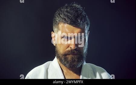 Nahaufnahme Porträt ernsthafter Karatekämpfer, der sich auf den Wettkampf vorbereitet. Starker muskulöser Athlet Mann in weißem Kimono für Sambo, Jiu Jitsu und andere Kampfhandlungen Stockfoto