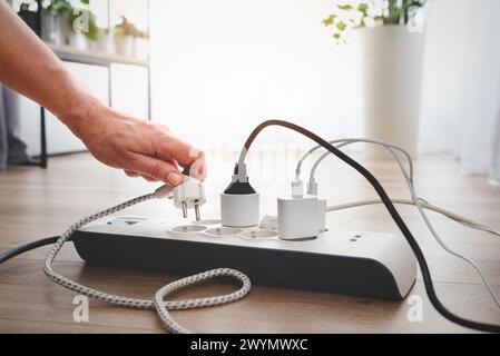 Mann, der den Netzstecker einsteckt. Steckdose zu Hause. Stockfoto