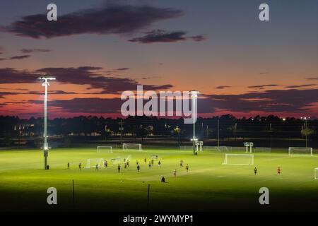 Beleuchtete öffentliche Sportarena in North Port, Florida, wo die Leute bei Sonnenuntergang im Grasfußballstadion Fußball spielen. Konzept für Outdoor-Aktivitäten Stockfoto