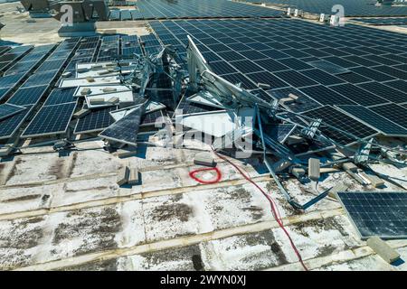 Draufsicht der durch den Hurrikan Ian zerstörten Photovoltaik-Solarpaneele, die auf dem Dach des Industriebaues zur Erzeugung von ökologischem Strom montiert sind Stockfoto