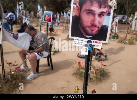 "Wir werden die Melodie nicht aufhalten" steht auf einer Karte neben einem Foto von Dor Avian, einem der Israelis, die während des Massakers am 7. Oktober 2023 bei der Nova-Tanz- und Musikparty getötet wurden, während einer Gedenkstätte in Re'im, Süd-Israel, anlässlich des sechsmonatigen Jahrestages des Hamas-Angriffs am 7. Oktober 2024. Rund 325 Israelis und Ausländer wurden von Hamas-Terroristen ermordet, die am 7. Oktober den Grenzzaun durchbrachen und Dutzende Gemeinden entlang der Grenze attackierten. Der Vater eines anderen Israelis trauert, als er sein Gesicht mit einem T-Shirt mit dem Porträt seines Sohnes abwischt (L). Pho Stockfoto