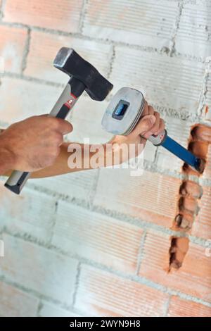 Maurer, der eine Nut in der Ziegelwand macht, um elektrische Drähte zu platzieren. Hammer- und Meißelhandwerkzeuge. Konstruktion. Bauarbeiten. Donostia. San Sebastian. Gipuzkoa. Baskenland. Spanien. Stockfoto