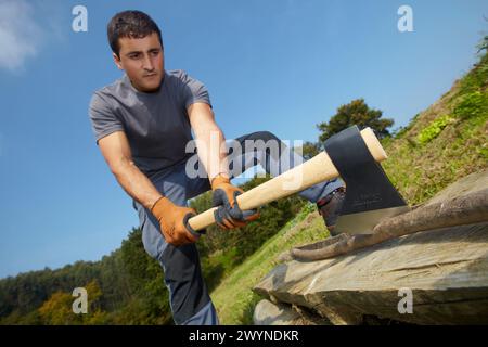 Landwirt, der Holz mit einer Axt, Axt, Handwerkzeug für Landwirtschaft und Gartenarbeit zerkleinert, Usurbil, Gipuzkoa, Baskenland, Spanien. Stockfoto