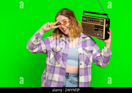 Glückliche junge kaukasierin, die Musik im Retro-Tonbandspieler hört, Disco tanzt Lieblingstitel, Spaß hat, unterhaltsam, Fan von Vintage-Technologien. Mädchen isoliert auf Chroma Key Hintergrund Stockfoto