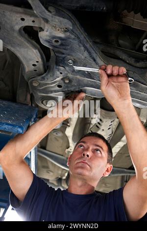 Arbeiter mit Ringschlüssel in der Autowerkstatt. Stockfoto