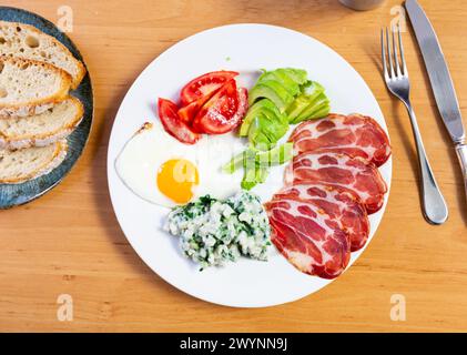 Das amerikanische Frühstück umfasst Spiegelei, Schweinespeck, Tomatenscheiben und Avocado, ergänzt durch Brot Stockfoto