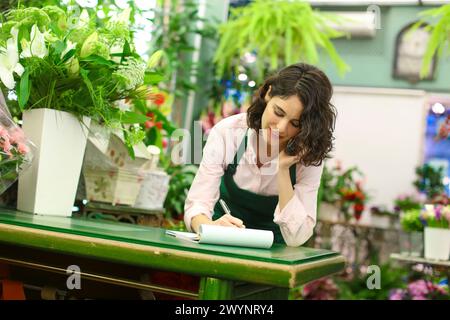 Florist im Blumengeschäft, der eine Bestellung von einem Kunden am Telefon entgegennimmt. Stockfoto