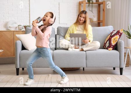 Die arbeitende junge Frau war gestresst, dass ihre laute kleine Tochter zu Hause singt Stockfoto