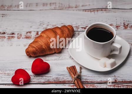 Tasse Kaffee mit Croissant für ein romantisches Frühstück am Morgen. Konzept einer Grußkarte für Valentinstag oder Hochzeit Stockfoto