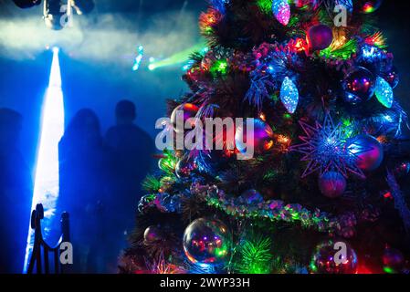 Wunderschön dekoriert mit Kugeln und Weihnachtsspielzeug festlicher Weihnachtsbaum in der Nacht mit farbenfrohem hellem Licht Stockfoto