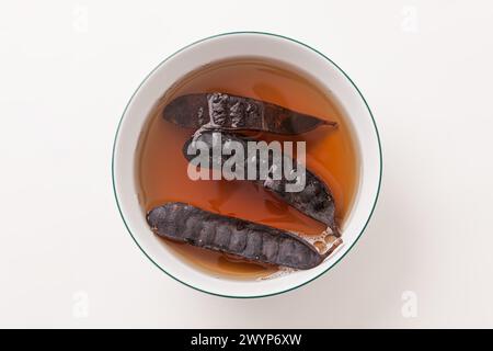 Die getrocknete Gleditsia Frucht oder Dorny Honey Locust werden in einer Schüssel Wasser eingeweicht Stockfoto