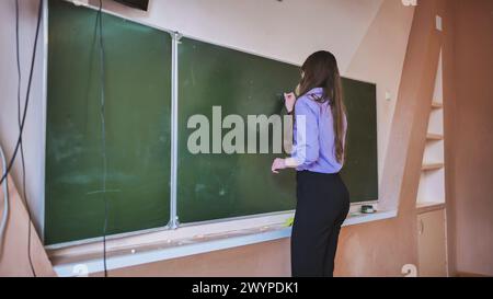 Ein Schulmädchen schreibt an die Tafel. Stockfoto