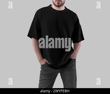 Modell eines schwarzen Oversize-T-Shirts auf einem Mann mit den Händen in den Taschen in dunkler Jeans, Vorderansicht, für Design, Branding. Ein weites Hemd auf einem Kerl, isoliert Stockfoto