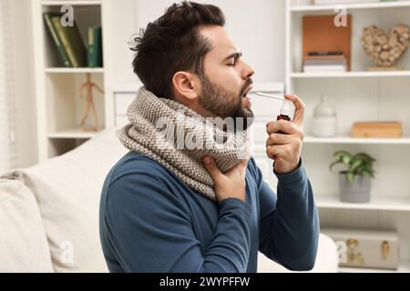 Junger Mann mit Schal mit Kehlspray in Innenräumen Stockfoto