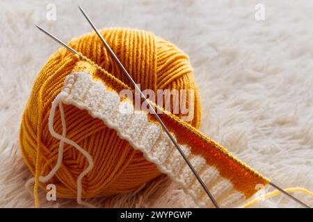 Gelbes Strickgarn und Stricknadeln. Strickmode Mode. Wollsocken und Nadeln. Strickhobbyarbeit. Handwerkskleidung. Handarbeit-Konzept. Stockfoto