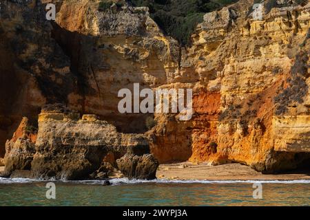 Abgeschiedener, versteckter Strand unter malerischen Klippen, vom Meer aus gesehen in Lagos, Algarve, Faro District, Portugal. Stockfoto