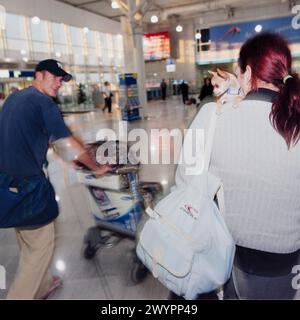 Ein weibliches Haustier Chihuaua nimmt Augenkontakt mit einem Mann auf, während beide Passagiere am 29. Juli 2002 in Paris über die Abflughalle am Flughafen Le Bourget laufen. Stockfoto