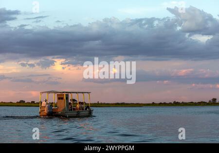 Ein Touristenboot auf einer Sundowner-Bootstour auf dem Chobe River im Chobe National Park Stockfoto