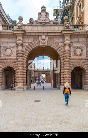 Eine Frau nähert sich den großen Toren des schwedischen Parlamentsgebäudes Riksdagshuset, das sich in Stockholm befindet, und fängt das Wesen historischer und politischer Bedeutung ein. Stockfoto