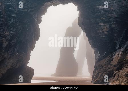 Playa de Las Catedrales bei Nebel. Catedrais Strand in Ribadeo, Lugo, Galicien, Spanien. Natürliche Bögen des Cathedrals Strandes. Moody Rock Formationen auf Stockfoto