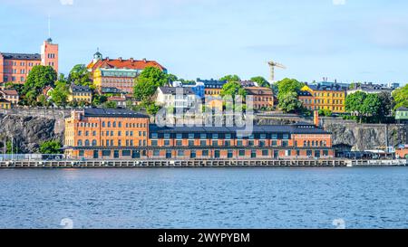 Der Blick auf das Fotografiska Museum in Stockholm, Schweden, genießt unter einem klaren blauen Himmel, mit lebhaften Gebäuden auf dem felsigen Gelände im Hintergrund. Stockfoto