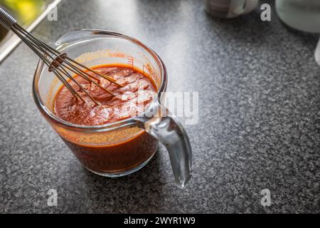 Rühren der Enchilada-roten Soße im Glas-Messbecher. Stockfoto