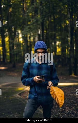 Reisender mit Rucksack im tropischen Dschungel mit Smartphone Stockfoto