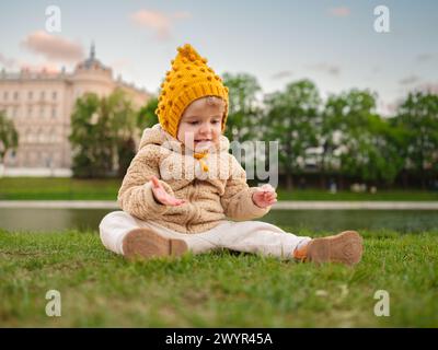 Ein dreijähriges Mädchen sitzt auf dem Gras im Park. Stockfoto