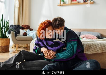 Gut aussehendes, liebevolles und fröhliches Paar in lebendigen Kleidern, das zu Hause viel Zeit hat und sich umarmt Stockfoto