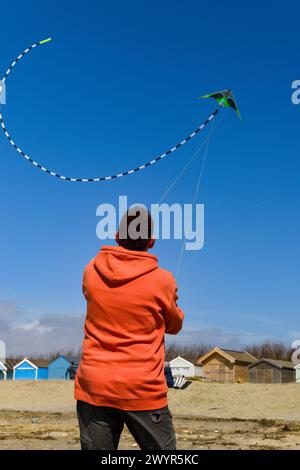 Mann, der einen Stunt-Drachen am West Wittering Beach in der Nähe von Chichester fliegt, während Storm Kathleen an der Südküste windet, im Frühjahr 2024 Stockfoto