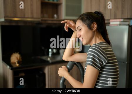 Die junge Hausfrau wischt sich den Schweiß von der Stirn, müde von der Hausarbeit Stockfoto