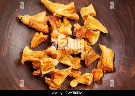 Stapel getrockneter Ananasstücke. Getrocknete gelbe Bio-Früchte in rustikaler Holzschale Nahaufnahme Stockfoto