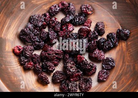 Süße trockene Kirsche in rustikaler Holzschale Nahaufnahme. Nahrhafte getrocknete Beeren. Gesunder Vitaminbestandteil. Draufsicht. Drehung Stockfoto