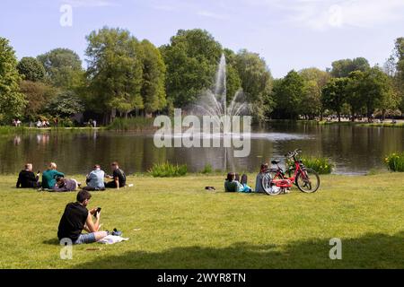 Junge Menschen genießen das schöne Wetter am Wasser im Vondelpark in Amsterdam. Stockfoto