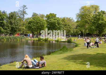 Junge Menschen genießen das schöne Wetter am Wasser im Vondelpark in Amsterdam. Stockfoto